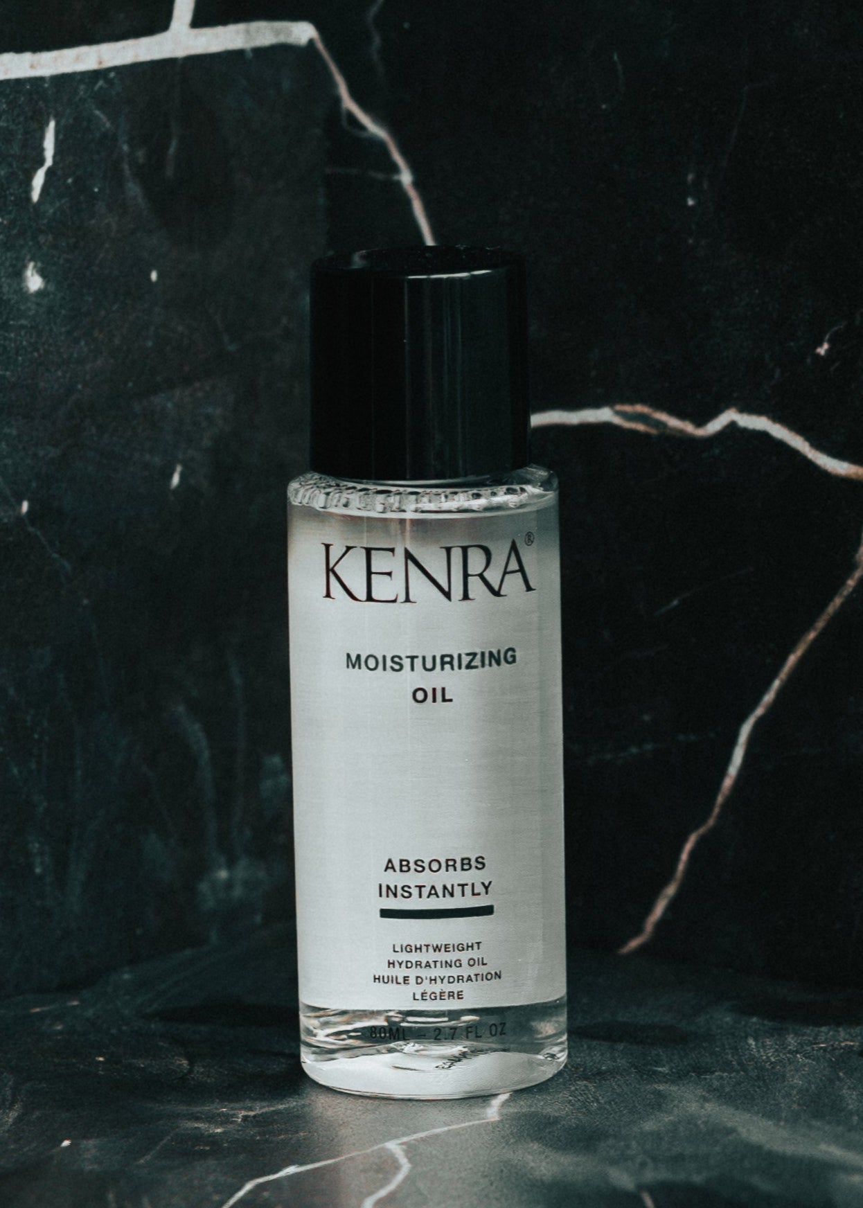 Kenra moisturizing oil bottle on a dark marble background